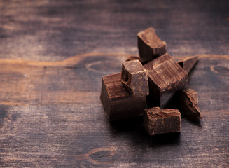 Pieces  dark chocolate on a wooden background and space for text
