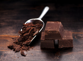 dark chocolate pieces on a wooden background and metal scoop