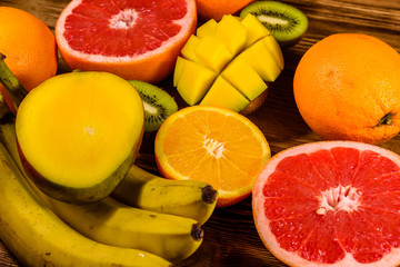 Still life with exotic fruits. Bananas, mango, oranges, grapefruit and kiwi fruits on wooden table