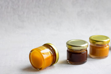 Three Small glass jar with metal cap with different kinds and colours of honey put in line isolate...