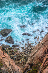 Blue sea with rocky shore in sunny afternoon