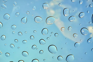 Water drops on glass window over blue sky. Water drops background.