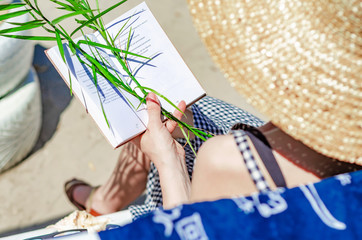 Fototapeta premium Girl in a straw hat reads a book on a bench