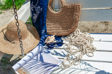 Sunglasses on a white bench with a magazine, rope, hat and bag. Beach holidays, travel, resort