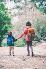 A woman walks with her son through the forest.