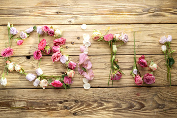 Word Flowers Letters Lined Up With Flowers On An Old Wooden Background