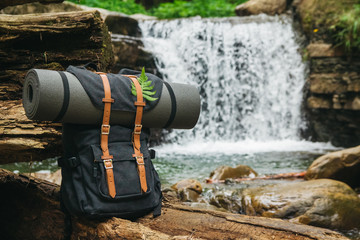 Hipster hiker tourist backpack on the background of the river and the waterfall , traveler relax holiday concept, travel adventure.