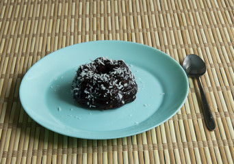Chocolate cake with coconut, cherries and tea on a plate