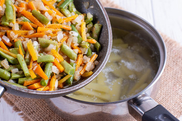 Onions, carrots, green beans and spices in a pan