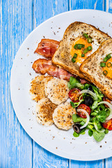 Breakfast - toasted bread with fried egg, bacon and vegetables