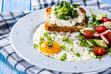 Breakfast - fried egg, toasts and vegetable salad