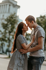 Fototapeta premium Young couple in love teenagers dressed in casual style walking together and kissing on city street
