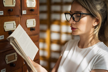 Fototapeta premium Blonde woman reading a book in public library