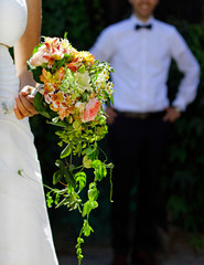 Newlyweds on a sunny day while the bride presents her flower boquet