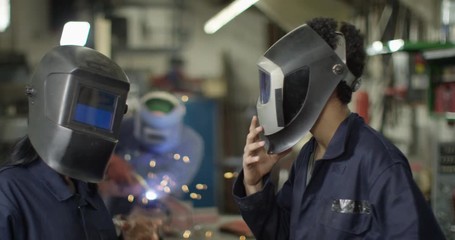 4K Portrait smiling male & female mechanics in garage workshop. Slow motion.