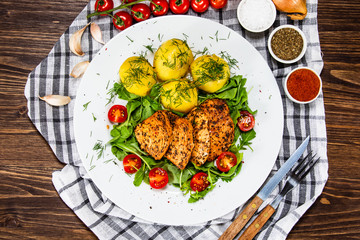 Grilled chicken fillet and vegetables on white plate