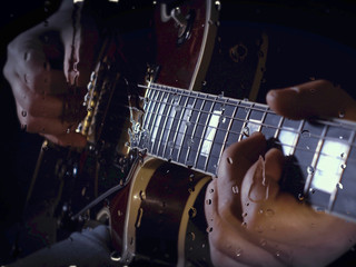 musician playing guitar at studio behind the glass with water drops