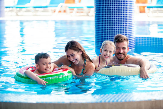 Mom And Dad Playing With Their Kids In The Swimming Pool