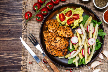 Grilled chicken fillet and vegetables on wooden table