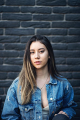 Young caucasian girl with strike hair posing on black brick wall