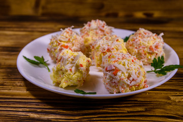 White plate with crab-cheese balls on wooden table