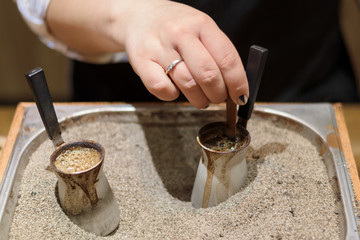 Hand of woman holding pots and making turkish coffee
