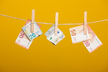 Billetes de Euro sobre fondo amarillo, colgados de una cuerda y sujetos por unas pinzas de madera...