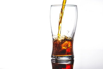 pouring cola into glass with ice on white background Copy space