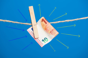 Billetes de Euro sobre fondo azul, colgados de una cuerda y sujetos por pinzas de extender la ropa. La banca lo utiliza como materia prima, las empresas para pagar a sus empleados.