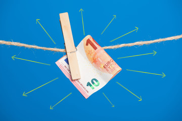 Billetes de Euro sobre fondo azul, colgados de una cuerda y sujetos por pinzas de extender la ropa....