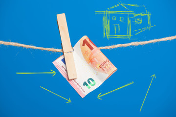 Billetes de Euro sobre fondo azul, colgados de una cuerda y sujetos por pinzas de extender la ropa....
