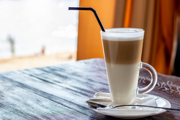 Latte coffee in a glass on a wooden table, copy space