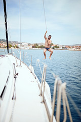 Happy man jumping from sailing boat in sea. .