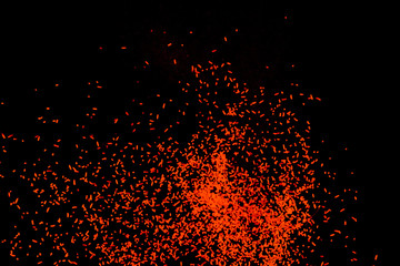 Orange dust particles explosioon on black background.