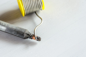 solder wire and soldering iron with wooden handle on gray background