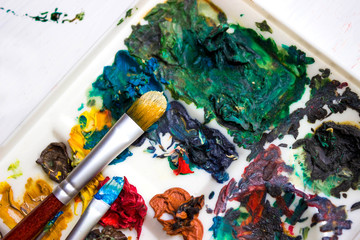 Artist's brushes and old palette with oil paints, drawing and creativity. Toned