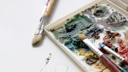 Artist's brushes and old palette with oil paints, drawing and creativity. Toned