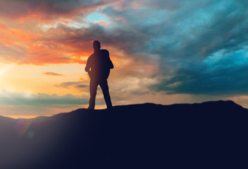 travel, tourism, hike and people concept - traveller with backpack standing on edge of hill over sunset background