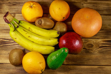 Assortment of tropical fruits on wooden table. Still life with bananas, mango, oranges, avocado, grapefruit and kiwi fruits