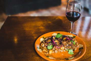 Plato de risotto con pulpo y copa de vino tinto en mesa de restaurante