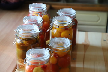 Fototapeta na wymiar Tomatoes of different varieties with different juices in glass jars homemade preparations