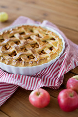 food, culinary and baking concept - apple pie and kitchen towel on wooden table