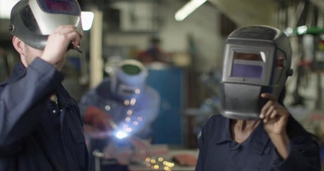 4K Portrait friendly smiling male & female welders in industrial workshop. Slow motion.