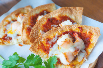 Set of crispy shrimp baked with chilli sauce and vegetable on paper and Thai parsley in wooden dish.