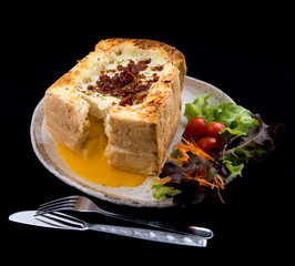 Egg-filled baked bread with crispy bacon on top
