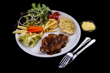 Pork steak, black pepper sauce served with salad vegetables and garlic bread