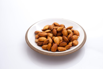 Peeled almond in ceramic plate isolated on white background