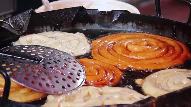 Making of traditional street food jilebi ,frying deep of maida or plain flour batter before soaking in sugary syrup 