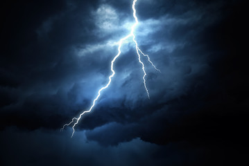 Lightning strike on a cloudy dark rainy sky.