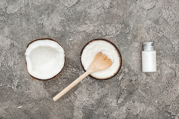 flat lay with coconuts, wooden spoon and coconut cream on grey textured background